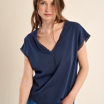 T-shirt azul escuro com decote em V e bordas em renda, usada com calças de ganga azuis