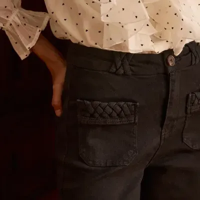 Calças pretas com bolso trançado e blusa branca com corações pretos e folhos