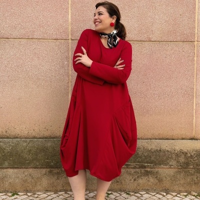 Mulher com vestido vermelho e acessórios em parede rosa