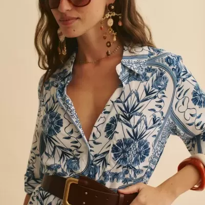 Mulher com vestido azul e branco floral, cinto castanho e óculos de sol castanhos grandes