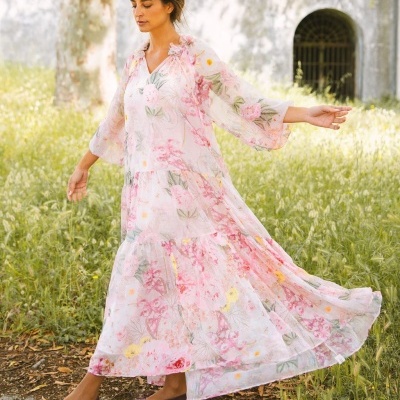 Vestido comprido floral feminino em tecido leve, usado com sapatos castanhos, em ambiente exterior