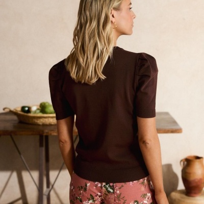 Mulher de costas com camisola castanha e calças florais rosas