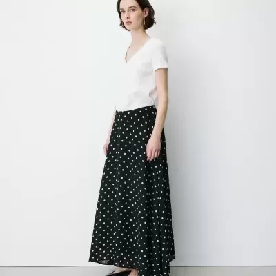 Mulher com t-shirt branca e saia preta com bolinhas brancas