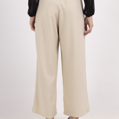 Calças largas bege com camisa preta e sapatos pretos vistas por trás