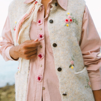 Colete de malha bege bordado com flores e camisa rosa com botões florais