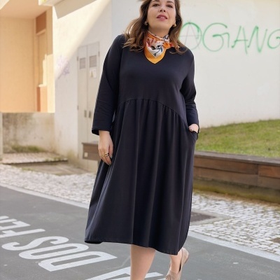 Mulher a usar vestido preto longo e cachecol colorido em ambiente urbano com grafitti