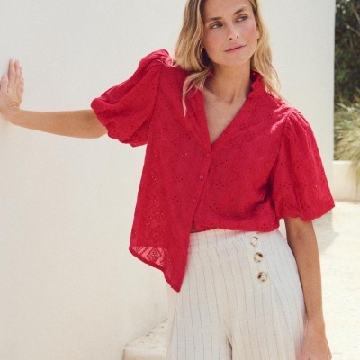 Blusa vermelha de renda com mangas bufantes e calças brancas com riscas finas e botões decorativos