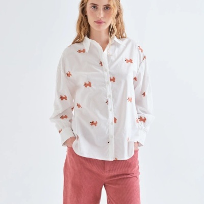 Camisa branca com padrão de cães castanhos e calças rosa de veludo cotelê