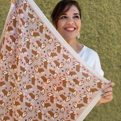 Lenço bege com padrão de cães Corgi castanhos e bolas laranja mostrado por mulher