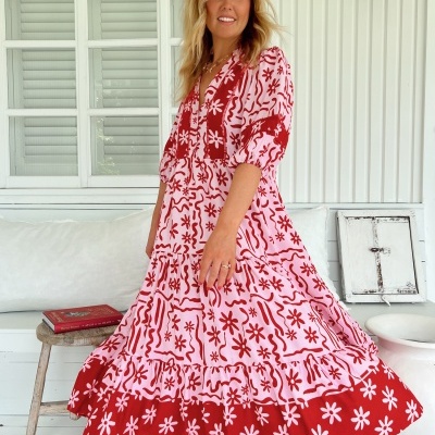 Vestido vermelho e branco com padrão floral em mulher numa varanda branca