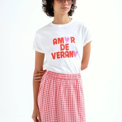 Mulher com t-shirt branca e saia vichy vermelha e branca.