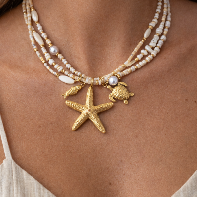 Colar com pingentes marinhos e contas brancas usado num pescoço feminino