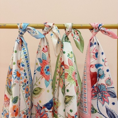 Lenços florais coloridos pendurados numa barra amarela.