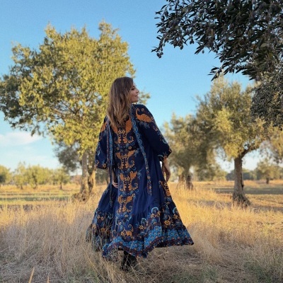 Vestido comprido azul com padrão floral e motivos laranja e azuis ao ar livre