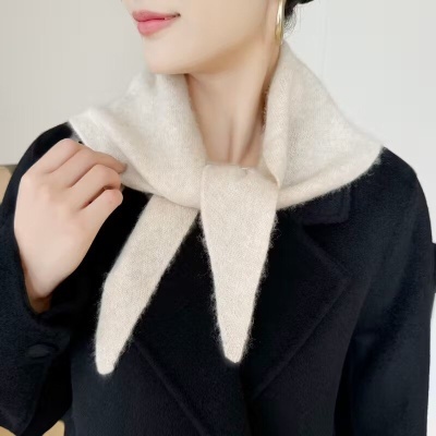 Cachecol bege felpudo sobre casaco preto com brinco dourado de argola