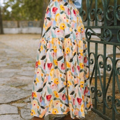 Saia longa floral colorida com cintura elástica ao ar livre junto a portão de ferro