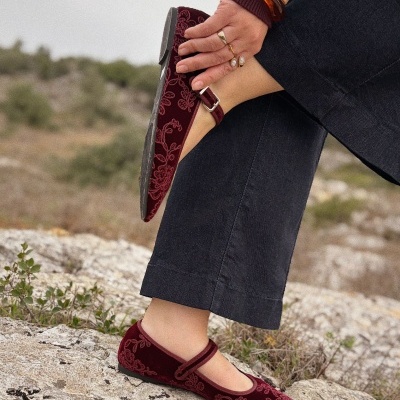 Sapatos Mary Jane bordô com padrão floral e sola preta em ambiente rochoso
