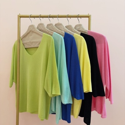 Seis camisas coloridas penduradas em cabides numa estrutura metálica