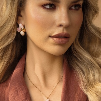 Mulher usando colar e brincos com pedras coloridas e detalhes dourados