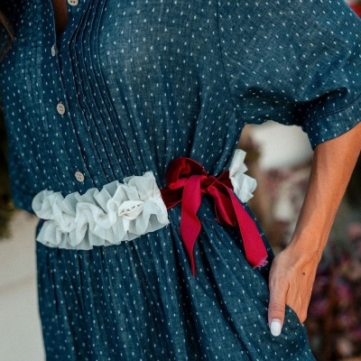 Vestido azul com padrão de pontos brancos e cinto branco com laço vermelho