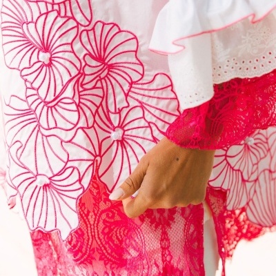 Roupas bordadas com flores vermelhas, renda vermelha e punho branco com detalhe rosa