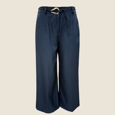 Calças largas azuis escuras com cinto dourado em fundo bege