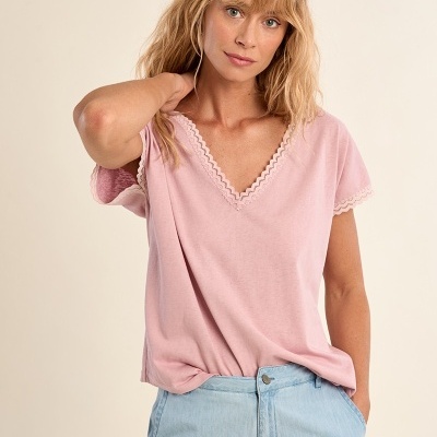 Mulher de cabelo loiro vestindo t-shirt rosa com detalhes em renda creme e calças de ganga azul claro