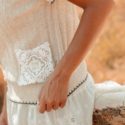 Roupa feminina bege com bolso branco em renda e saia branca com motivos florais