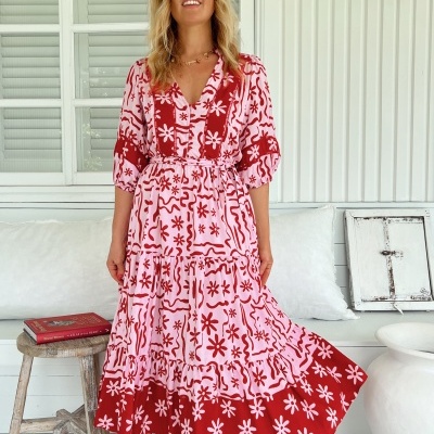 Vestido midi rosa e vermelho com padrão floral e linhas onduladas.