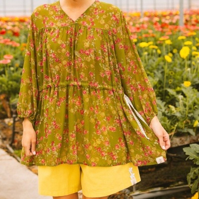Blusa floral verde-oliva e calções amarelos em estufa de flores