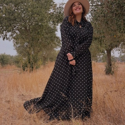 Vestido comprido preto de bolas brancas em campo seco com mulher e chapéu bege