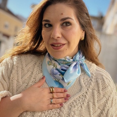 Mulher com lenço floral azul ao pescoço e camisola de lã creme tricotada