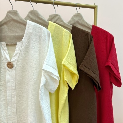 Quatro t-shirts coloridas penduradas num cabide dourado