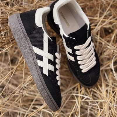 Sapatilhas desportivas preto e branco em fundo de palha seca