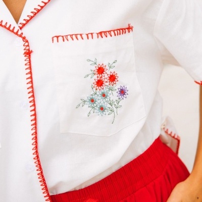 Blusa branca com bordado floral e costura vermelha, com saia/calças vermelhas de cintura elástica