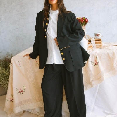 Mulher a usar blazer preto com botões dourados e calças largas pretas