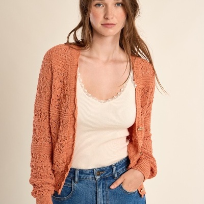 Mulher com casaco de malha laranja, camisola branca e jeans azul