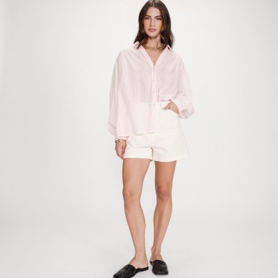 Mulher com camisa rosa, calções brancos e mocassins pretos