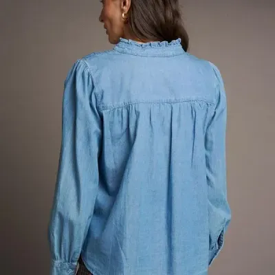 Blusa azul clara manga comprida vista de trás com gola franzida e pregas, calças xadrez cinzentas
