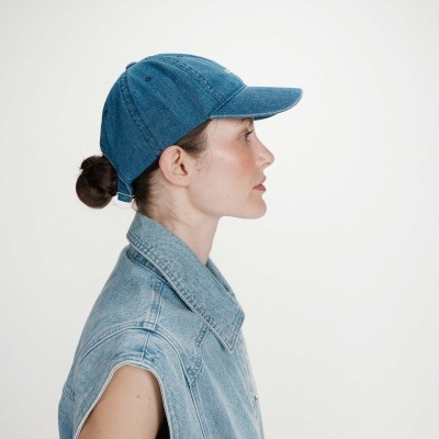 Pessoa de perfil a usar boné azul de tecido denim e colete azul claro de ganga sem mangas