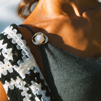 Broche dourado com pedra branca em vestido preto e croché preto e branco