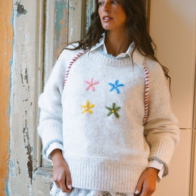 Camisola branca de malha com flores bordadas coloridas, usada sobre camisa branca com renda na barra