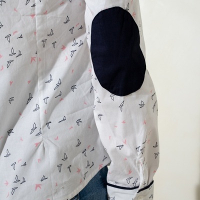 Camisa branca com padrão de aves e cotoveleira preta no cotovelo