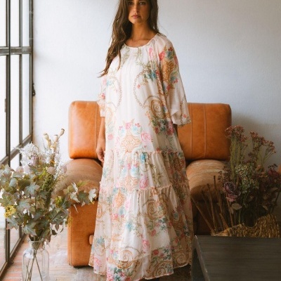 Vestido longo branco com padrão floral colorido em ambiente interior com sofá e flores