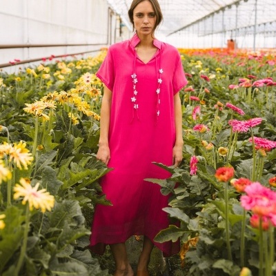 Vestido rosa feminino com detalhes florais e sandálias castanhas numa estufa de flores