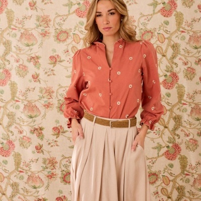 Blusa terracota bordada com flores brancas e saia plissada bege com cinto castanho
