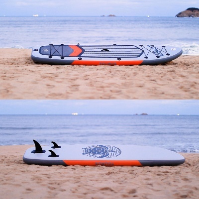 Prancha de paddle board insuflável cinzenta com detalhes laranja na praia perto do mar