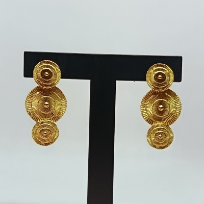 Brincos dourados com design de três círculos texturizados num suporte preto