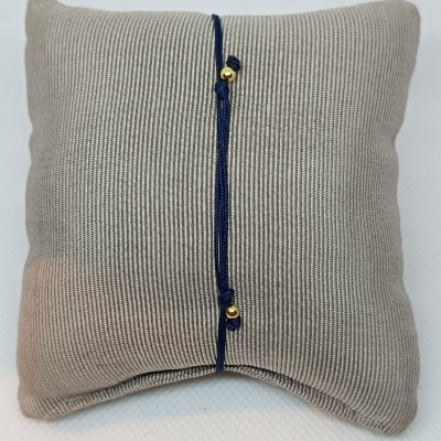 Almofada cinza com cordão azul e contas douradas