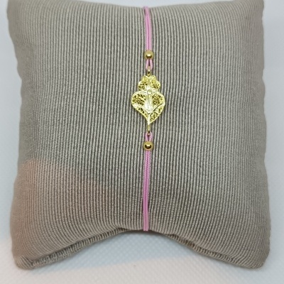 Pulseira com fio rosa e detalhe em forma de coração dourado sobre almofada cinzenta